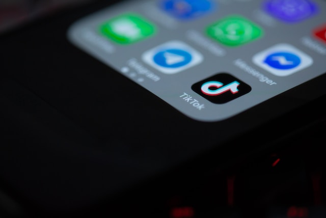 Nahaufnahme eines Smartphone-Bildschirms mit verschiedenen App-Symbolen, wobei das TikTok-Logo im Mittelpunkt steht.